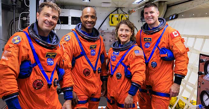 Four astronauts wearing orange spacesuits
