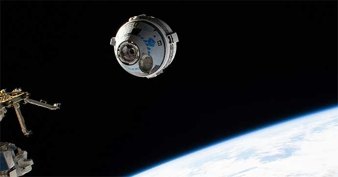 Un vaisseau spatial Starliner s'approche de la Station spatiale internationale. On voit une partie de la Terre