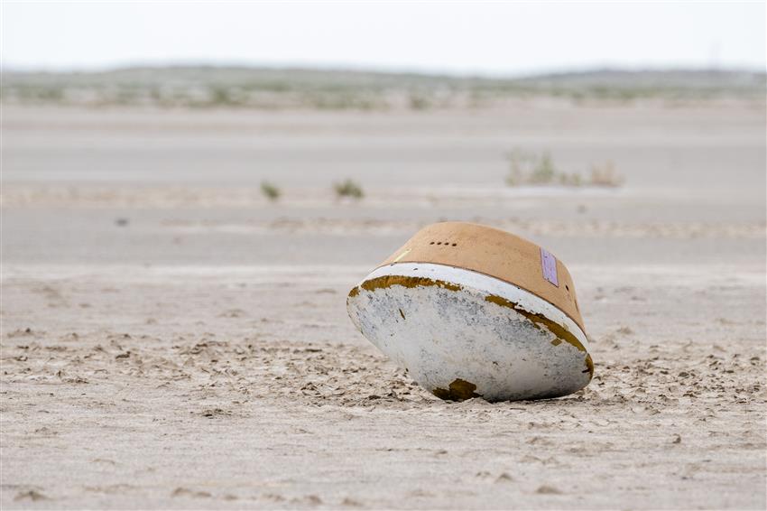 A capsule lying on the desert ground.