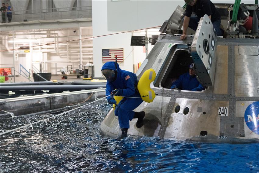 In a pool, Joshua evacuates a space capsule during water survival training.