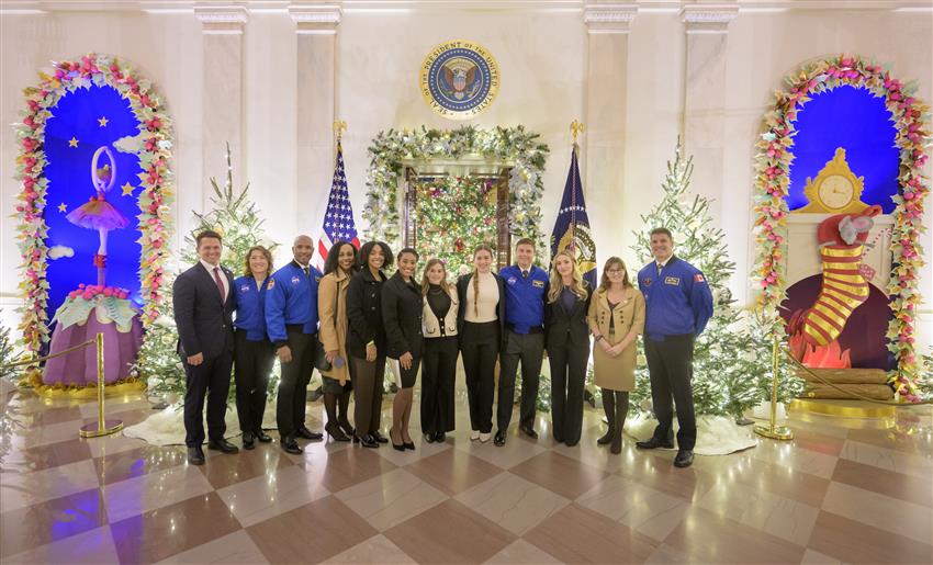 Photo de groupe des quatre astronautes avec des membres de leur famille dans une pièce décorée pour Noël.